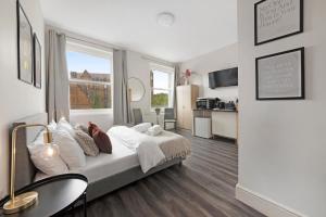 a white bedroom with a bed and a kitchen at Archway Station Studios - Double bed in London