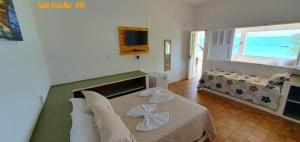 a bedroom with a bed and a couch and a television at Barra lounge in Maragogi