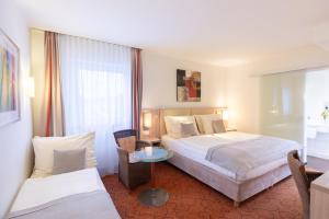 um quarto de hotel com duas camas e uma mesa em Novum Hotel Garden Bremen - Apartments em Bremen
