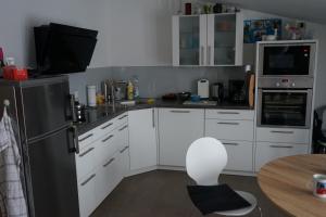 La cuisine est équipée de placards blancs et d'un réfrigérateur noir. dans l'établissement Urlaub im Alten Apfelgarten - Ferienwohnung Kastanienterrasse, à Sörup