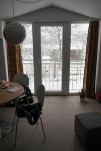 - un salon avec une table, des chaises et une grande fenêtre dans l'établissement Urlaub im Alten Apfelgarten - Ferienwohnung Kastanienterrasse, à Sörup