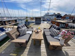 un patio con sofás y mesas en un barco en Hausboot Yara am Steg 1D, en Heiligenhafen