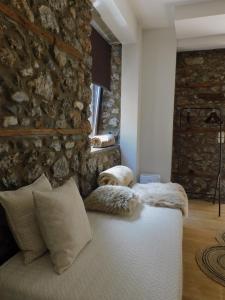 a bedroom with a stone wall and a bed with pillows at Olympus Stone Lodge in Litochoro