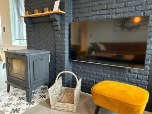 a living room with a wood stove and a yellow chair at Vakantiehuis Laurine in Deinze