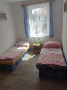 2 Einzelbetten in einem Zimmer mit Fenster in der Unterkunft Ubytování Pod hradem Dobronice 111 in Dobronice