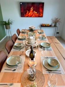 - une longue table en bois avec des assiettes et des verres à vin dans l'établissement Vakantiehuis Laurine, à Deinze