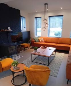 Elle comprend un salon doté d'un mobilier orange et d'une cheminée. dans l'établissement Vakantiehuis Laurine, à Deinze