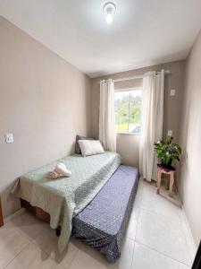a small bedroom with a bed and a window at Hospedagem Zilz in Pomerode