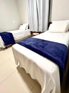two beds in a room with blue and white sheets at Chalé Travosa in Santo Amaro