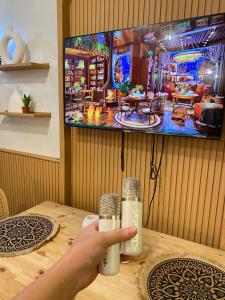 a person is holding a remote control at a table at Cozy Vibes near MOA & NAIA AIRPORT with NETFLIX,MINIVIDEOKE,BOARDGAMES-DUXE3 in Manila