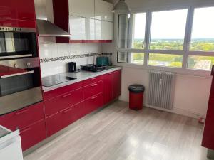 a kitchen with red cabinets and two windows at Paronamique villejean - proche métro in Rennes