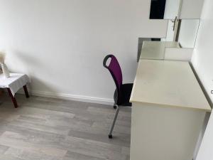 pusty pokój z biurkiem i fioletowym krzesłem w obiekcie Chambres d'Hôtes Kennedy, Villejean w mieście Rennes