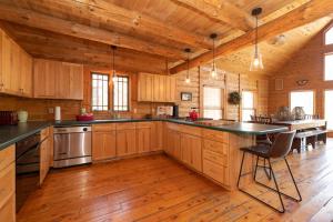 a large kitchen with wooden cabinets and a large island at Swan Lodge - Walking distance to downtown Saugatuck - Modern Cabin Getaway! in Saugatuck