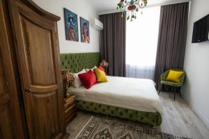 Un dormitorio con una cama verde con almohadas rojas y amarillas en Metelitsa Hotel, en Karagandá