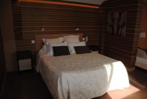 a bedroom with a bed with white sheets and pillows at Logis Hotel Du Casino Restaurant Le Mathelia in Vierville-sur-Mer