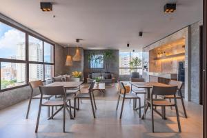 a dining room with tables and chairs and a living room at JSmart#304 - Apartamento em Fortaleza by Carpediem in Fortaleza