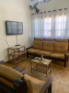 un salon avec un canapé et une télévision dans l'établissement Casa com Piscina Itanhaem, à Itanhaém