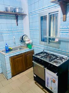 a blue tiled kitchen with a stove and a sink at Studio lumineux in Douala