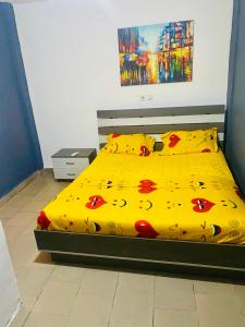 uma cama com um edredão amarelo e almofadas em Studio lumineux em Douala