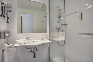 a white bathroom with a sink and a shower at Hotel Beaugrenelle Tour Eiffel in Paris