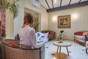 a woman reading a newspaper in a living room at Hotel Beaugrenelle Tour Eiffel in Paris