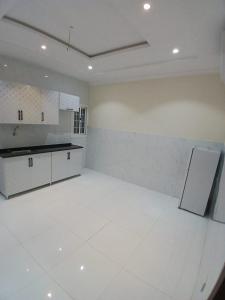 eine weiße Küche mit weißem Boden und einer Theke in der Unterkunft كيان التيسير للشقق المخدومة - Kayan Al Tayseer Serviced Apartments in Quwayzah