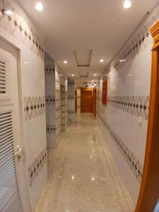 Quwayzah的住宿－كيان التيسير للشقق المخدومة - Kayan Al Tayseer Serviced Apartments，一条带白色瓷砖墙壁和长走廊的走廊