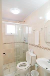y baño con aseo, ducha y lavamanos. en Xangri-La Praia Hotel, en Xangri-lá