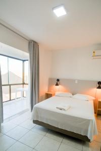 a bedroom with a white bed and a large window at Xangri-La Praia Hotel in Xangri-lá