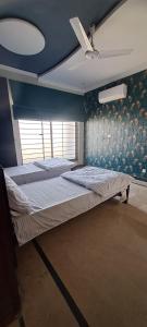 een bed in een kamer met een blauwe muur bij Concept Guest House in Islamabad