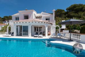 a white villa with a swimming pool and an umbrella at VILLA GERMAN 114 sea views in Son Bou