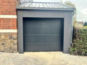 une porte de garage noire avec un toit métallique dans l'établissement Comme Che(z)Lui, à Spa
