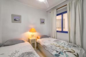 - 2 lits dans une chambre avec une fenêtre et une lampe dans l'établissement Luxe 1ste lijns appartement aan zee, à Playas de Orihuela 18 autres photos