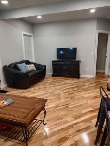 ein Wohnzimmer mit einem schwarzen Sofa und einem Flachbild-TV in der Unterkunft Modern, Newly-Renovated Home in the heart of LAX in La Crosse