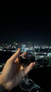 una persona sosteniendo una copa de vino por la noche en Luxury Heights with City View and River View, en Noida