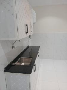 uma cozinha com um lavatório e armários brancos em كيان التيسير للشقق المخدومة - Kayan Al Tayseer Serviced Apartments em Quwayzah