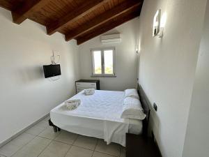 een slaapkamer met een wit bed en een televisie. bij Grazioso e panoramico appartamento in zona residenziale a Sant'Antioco C54 in SantʼAntìoco