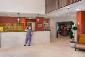 a man standing at a counter in a lobby at DOMITYS La Courtine in Melun