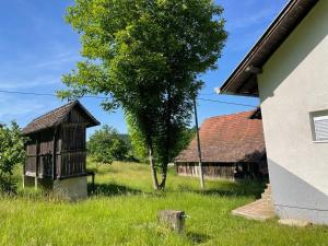 an old building and a tree in a field at Landhaus in Bosanska Dubica