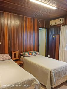 2 camas en una habitación con paredes de madera en Pátio Caiçara, Hospedagem, Eventos , Recepções, en Paranaguá