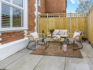 un patio avec une table et des chaises et une clôture dans l'établissement Railway Cottage - Stylish & Cosy Whitstable Oasis - Sleeps 2, à Whitstable