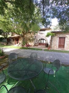 un tavolo in vetro e sedie in cortile di All'Ombra di San Damiano ad Assisi