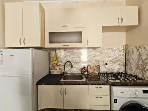 een keuken met witte kasten, een wastafel en een koelkast bij MY HOME GUEST HOUSE in GYUMRI in Gjoemri