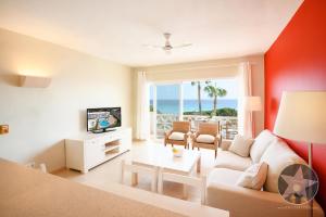 a living room with a couch and a tv and the ocean at Apartamento 4 en primera linea de mar in Santo Tomás