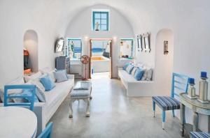 a living room with white walls and blue chairs at EverBlue Cave house by Thireon in Oia