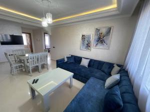a living room with a blue couch and a table at Appartement de vacances neuf: piscines et plage in Tangier +20 photos