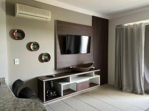 a living room with a television on a wall at Águas da Serra Apart hotel in Rio Quente