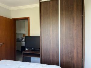 a bedroom with a television and a wooden closet at Águas da Serra Apart hotel in Rio Quente