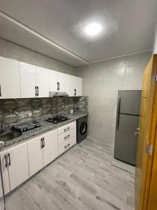 La cuisine est équipée de placards blancs et d'un réfrigérateur en acier inoxydable. dans l'établissement Kaa asras, à Tetouan