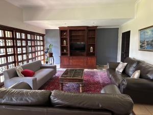 a living room with leather couches and a television at Beynespoort Farm in Cullinan
